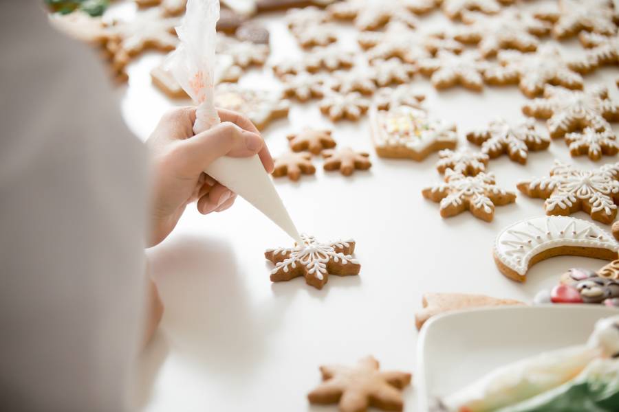 Close up of female confectioner hands icing gingerbread stars